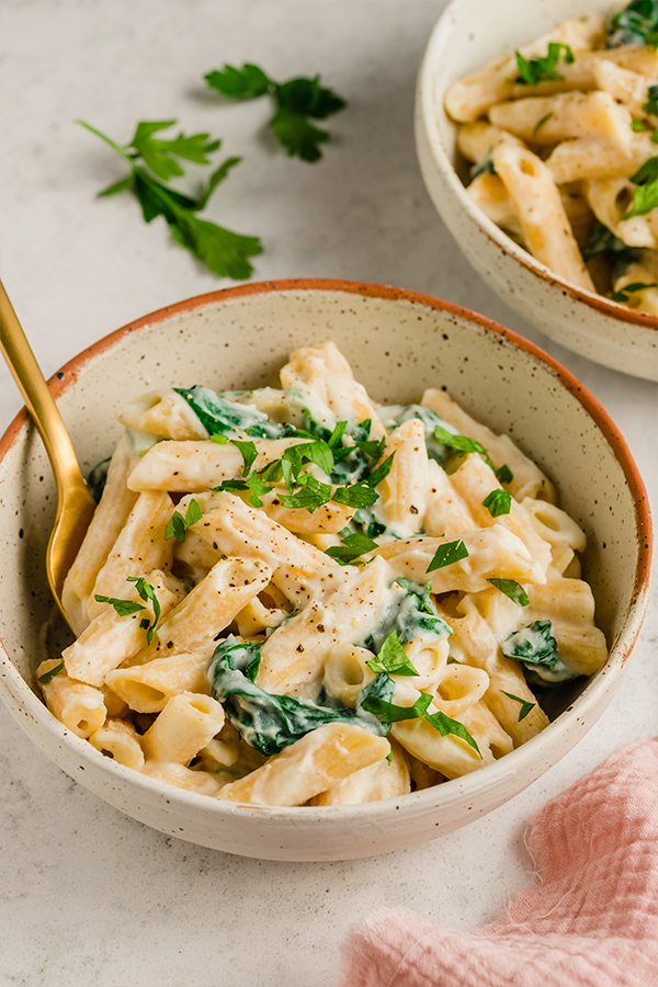 A bowl of Easy Penne Alfredo with chopped parsley on top.