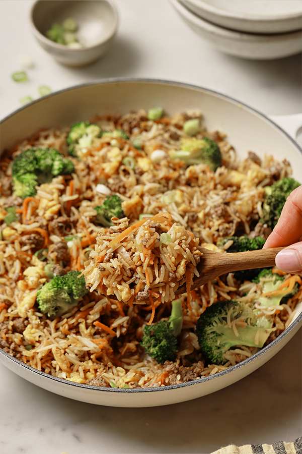 Person scooping ground beef fried rice.
