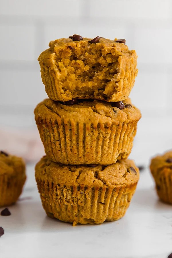 Stack of pumpkin muffins missing a bite.