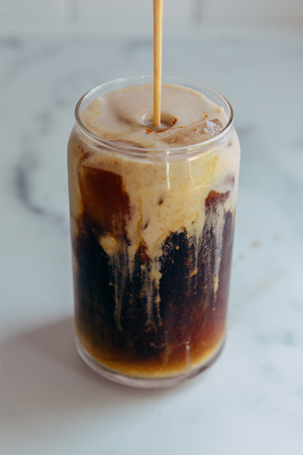 Creamer pouring into a glass with cold brew.