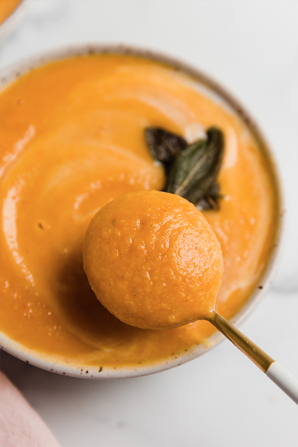 A spoon taking a spoonful of acorn squash soup.