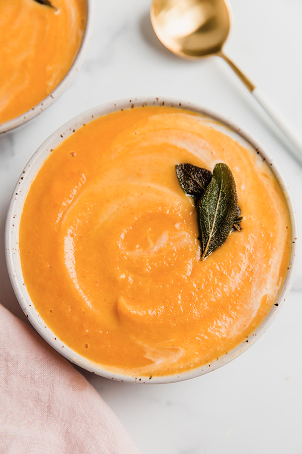 Bowl of roasted acorn squash soup with sage leaves.
