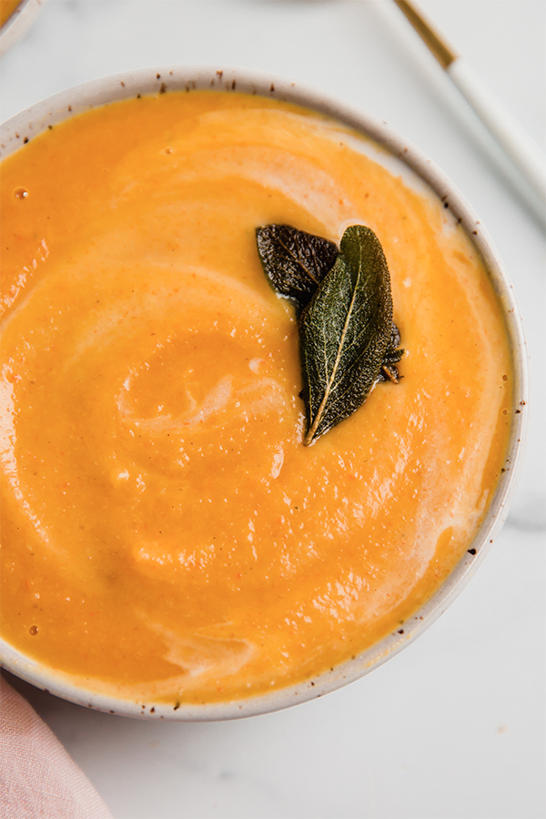 Sage leaves on a bowl of roasted acorn squash soup.