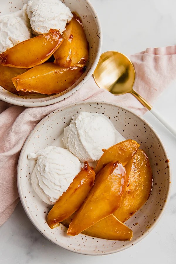 Caramelized pears served in a bowl with ice cream on the side.