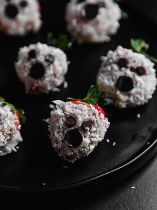 Plate of coconut butter covered strawberry ghosts.