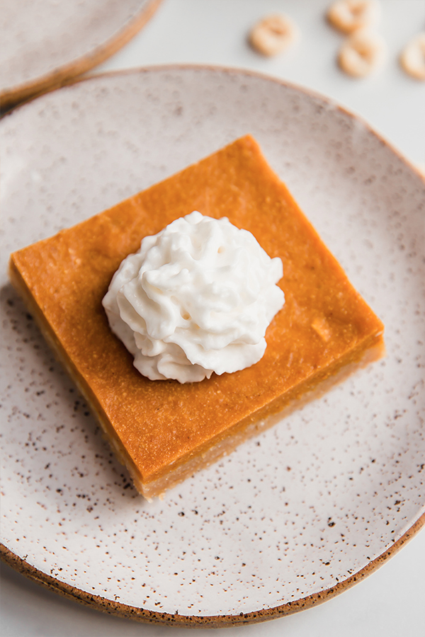 Pumpkin pie bar topped with whipped coconut cream.