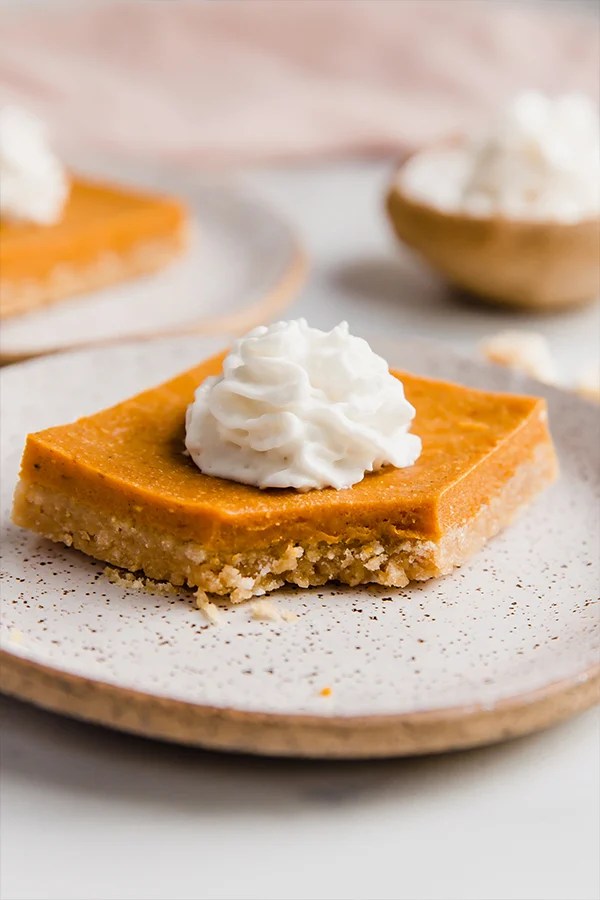 Pumpkin pie bar with cereal crust missing a bite.