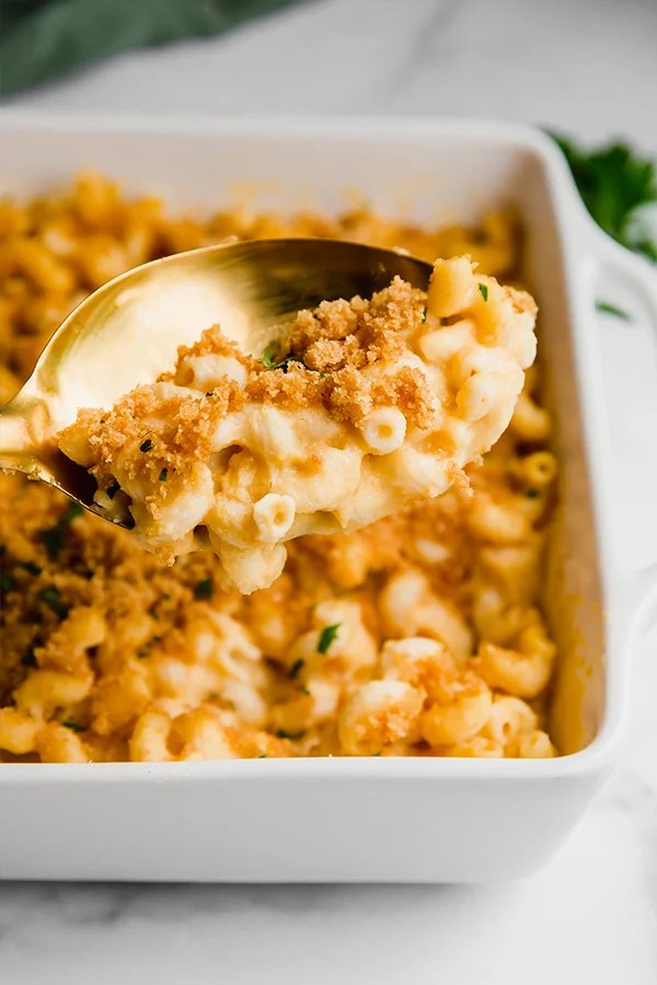 A spoon digging into a dish of mac and cheese.