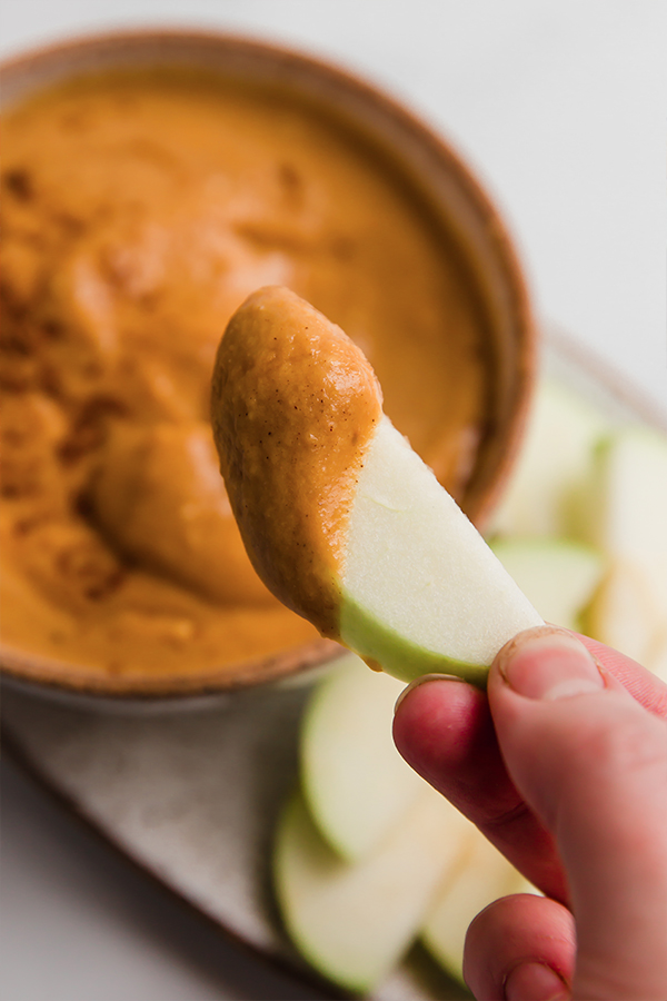 An apple covered in pumpkin pie dip.