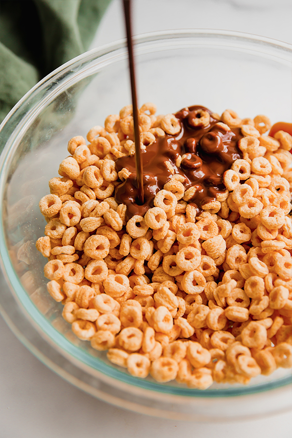 Chocolate pouring over cereal in a bowl.