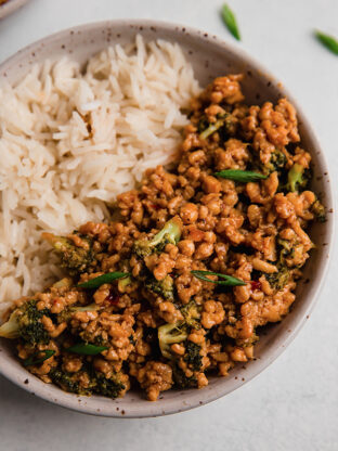 Firecracker ground chicken bowls topped with green onion and served with rice.
