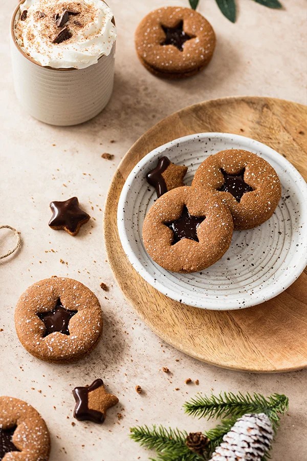 Gingerbread sandwich cookies with star cutouts on a plate.