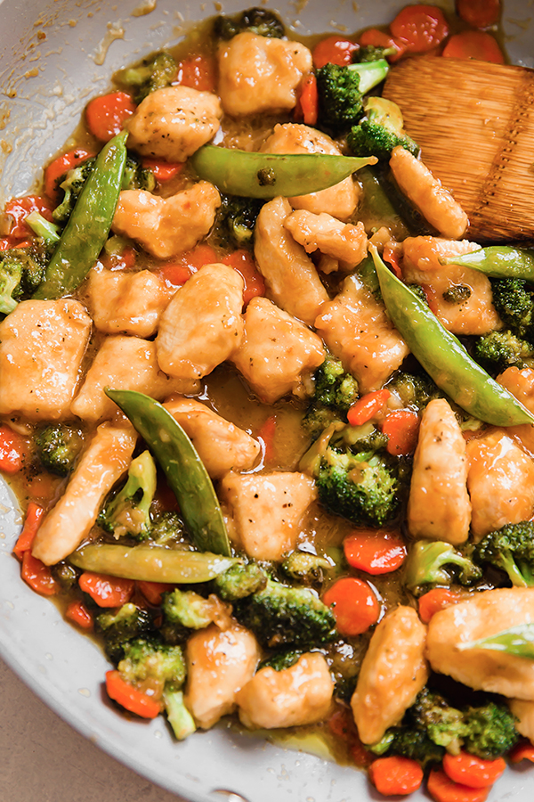Orange chicken stir fry in a pan.