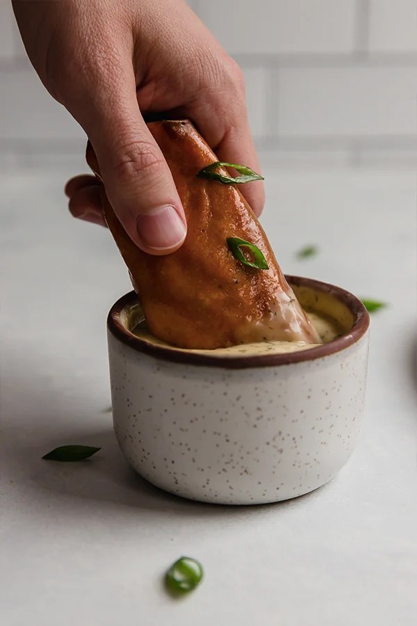 Dunking a buffalo chicken egg roll into sauce.