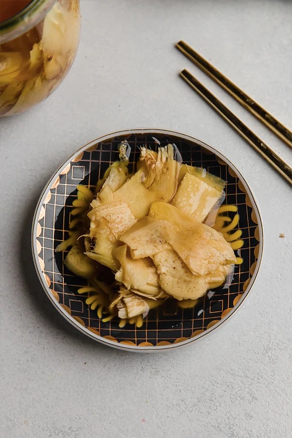 Chopsticks next to pickled ginger in a small bowl.