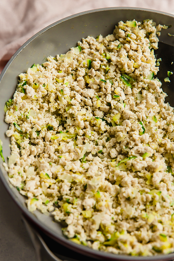 A skillet filled with ground turkey and zucchini cooking.