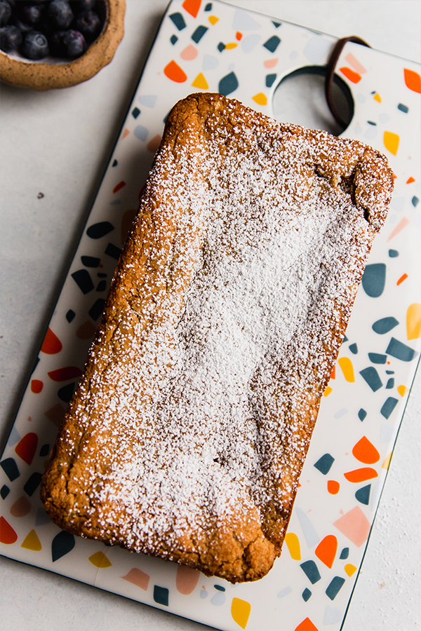 Loaf of applesauce pound cake on a colorful dish.