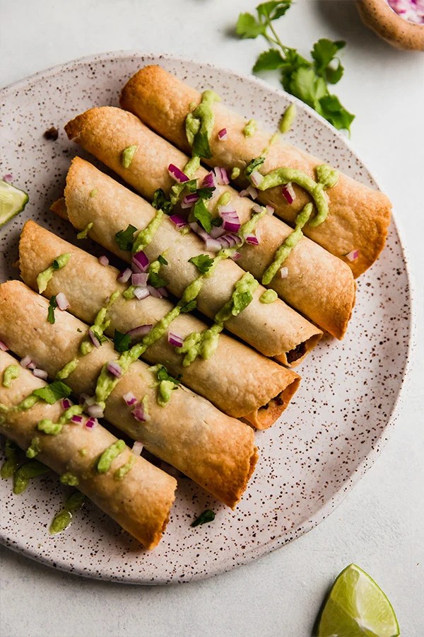 Sweet potato and beef breakfast taquitos drizzled with green sauce.