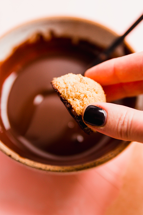 Dipping coconut macaroons in chocolate.