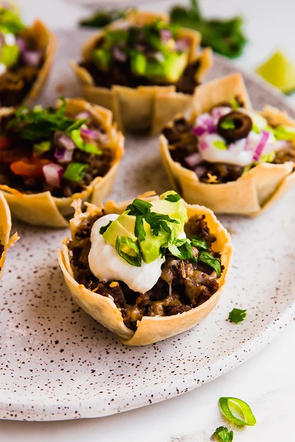 A plate with mini taco cups on it.