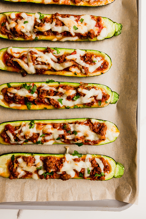 Several Beef Stuffed Zucchini Boats on a lined baking sheet.