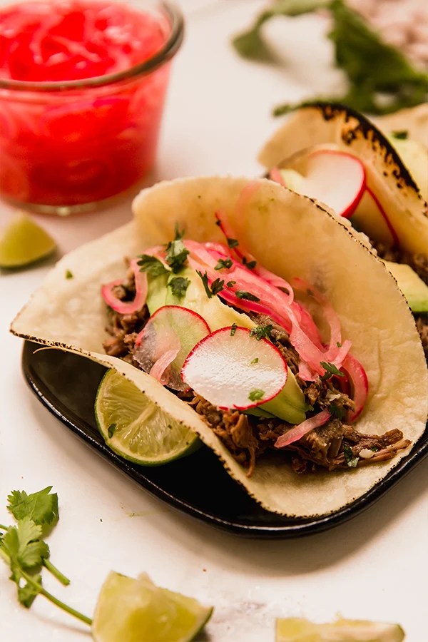Barbacoa beef tacos on a plate.