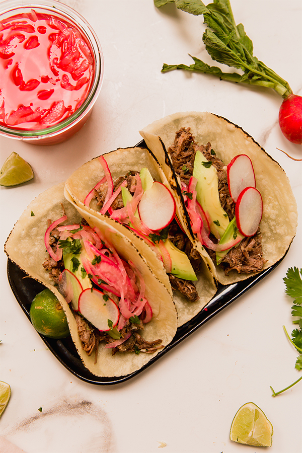 Plate with several barbacoa beef tacos.
