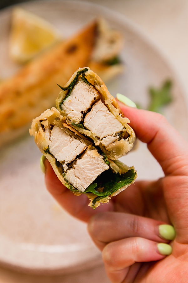 A gluten-free chicken pesto wrap cut in half.