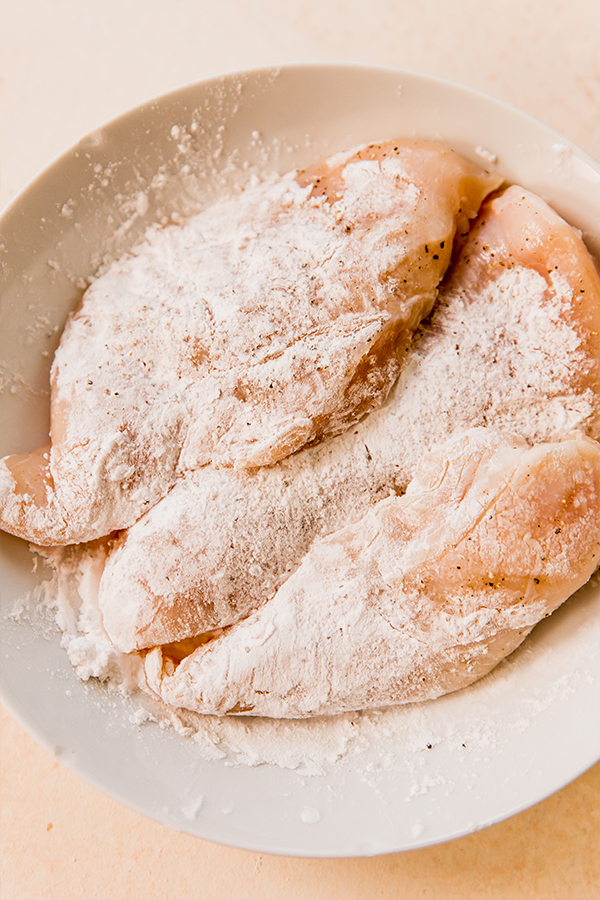 Chicken breasts covered in arrowroot powder before cooking.