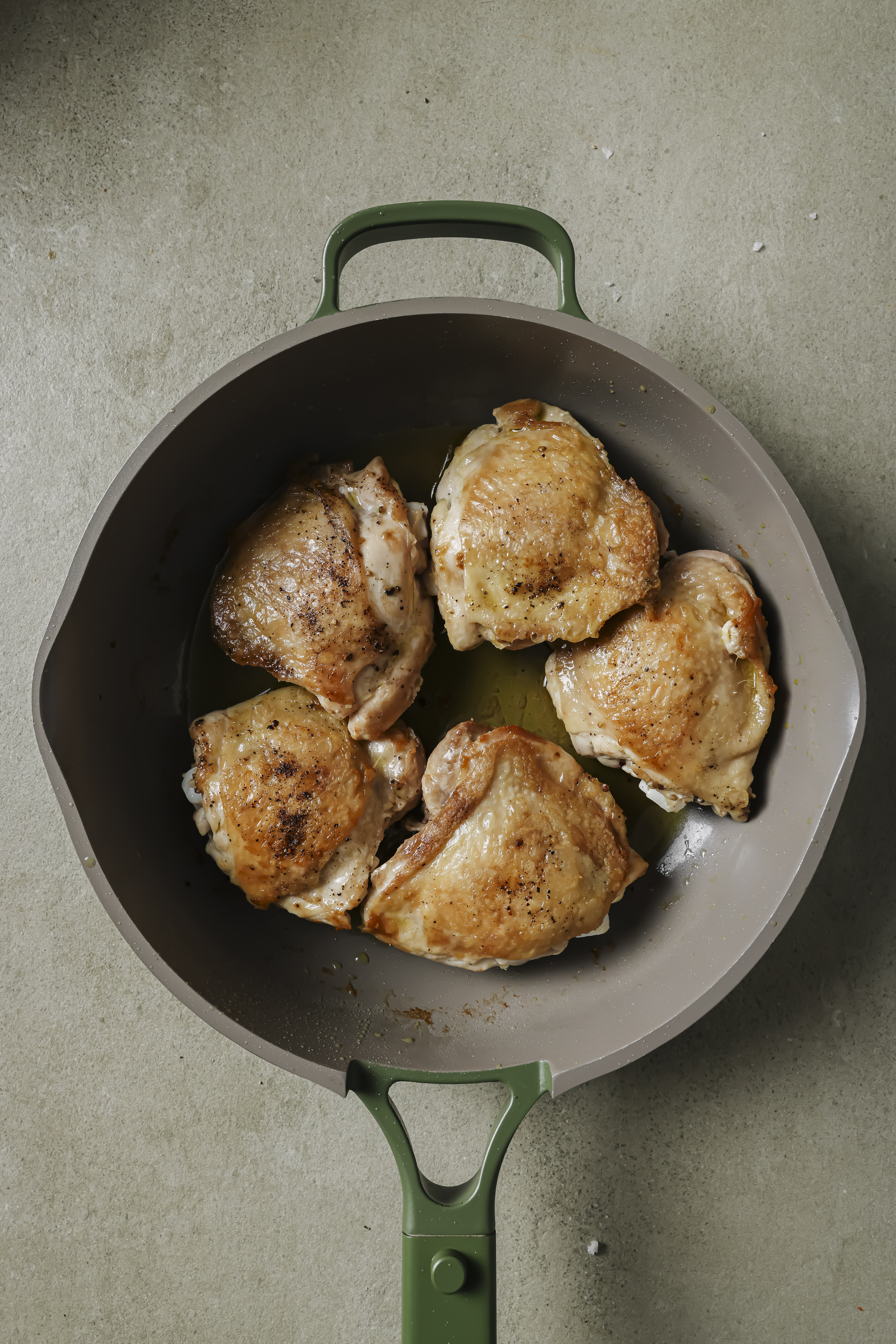 Chicken thighs crisped in a pan.