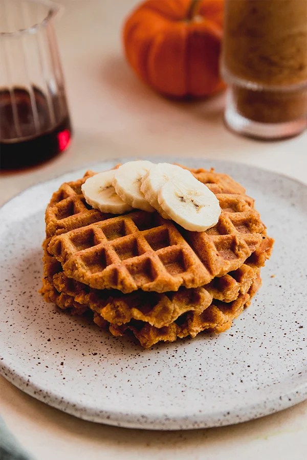 Pumpkin waffles stacked on a plate.