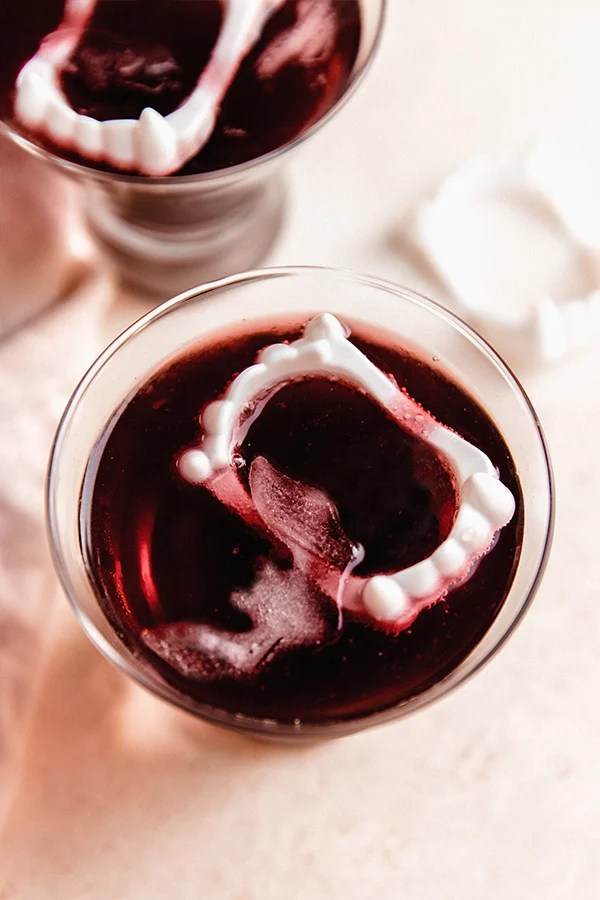 Fake vampire teeth floating in a glass of vampire mocktail.
