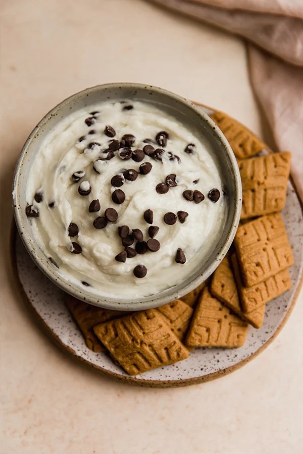 A bowl of cannoli dip with graham crackers around it.
