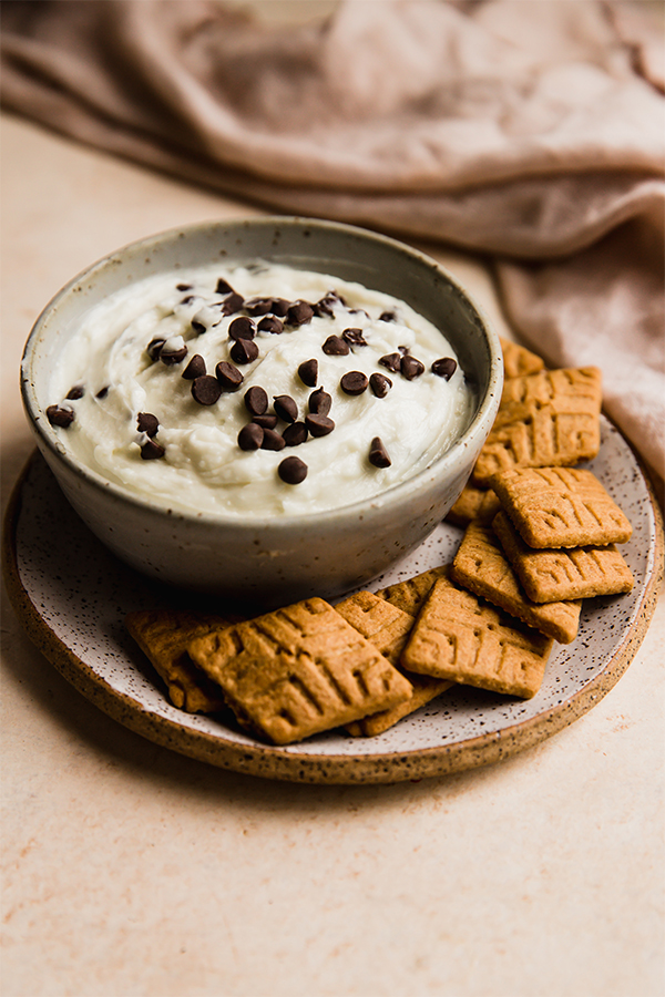 A bowl of cannoli dip with graham crackers around it.