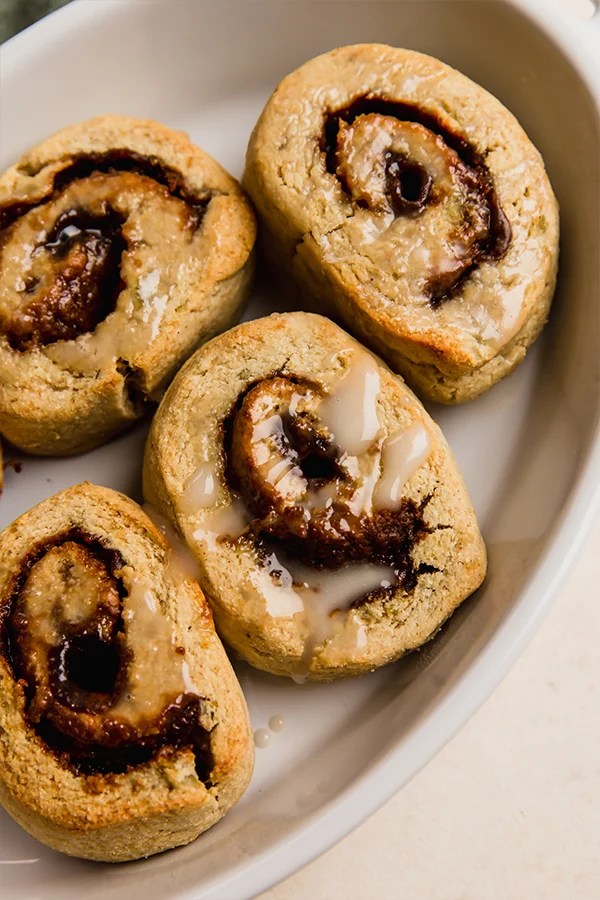 AIP gingerbread cinnamon rolls topped with icing in a baking dish.