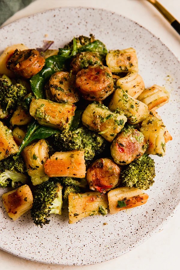 Gnocchi, sausage, and vegetables on a plate.
