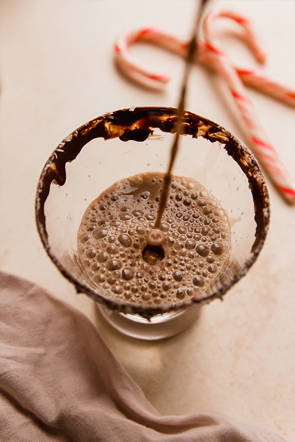 Peppermint mocktail pouring into a glass with a chocolate rim.