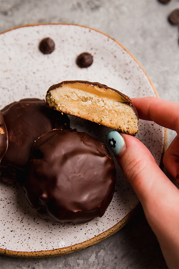 Plate of homemade Tagalong cookies, on of which is cut in half.