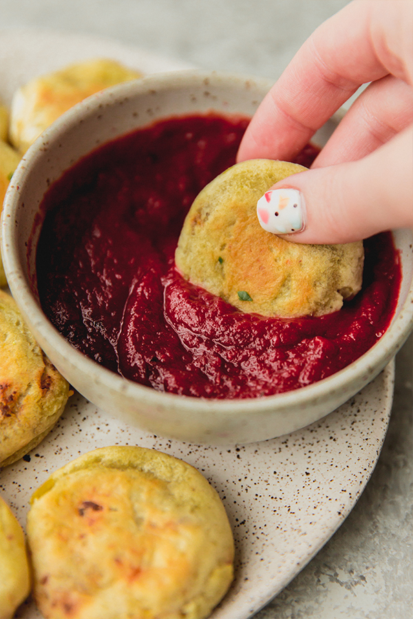 Someone dipping a pizza roll into nomato sauce.