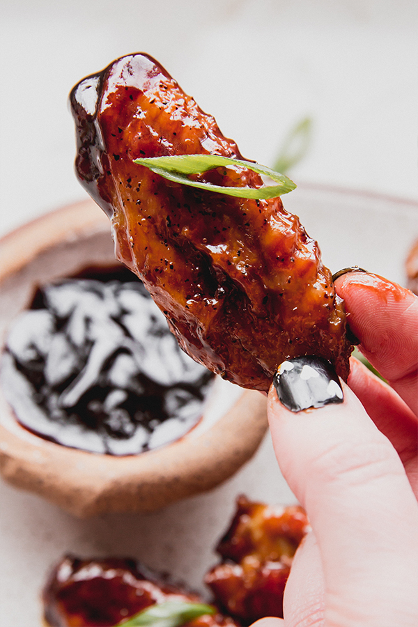 Person holding a General Tso\'s style chicken wing.