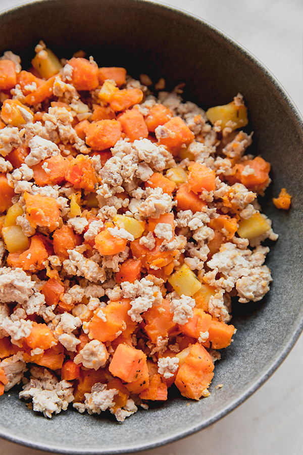Vegetable hash with orange vegetables in a pan.
