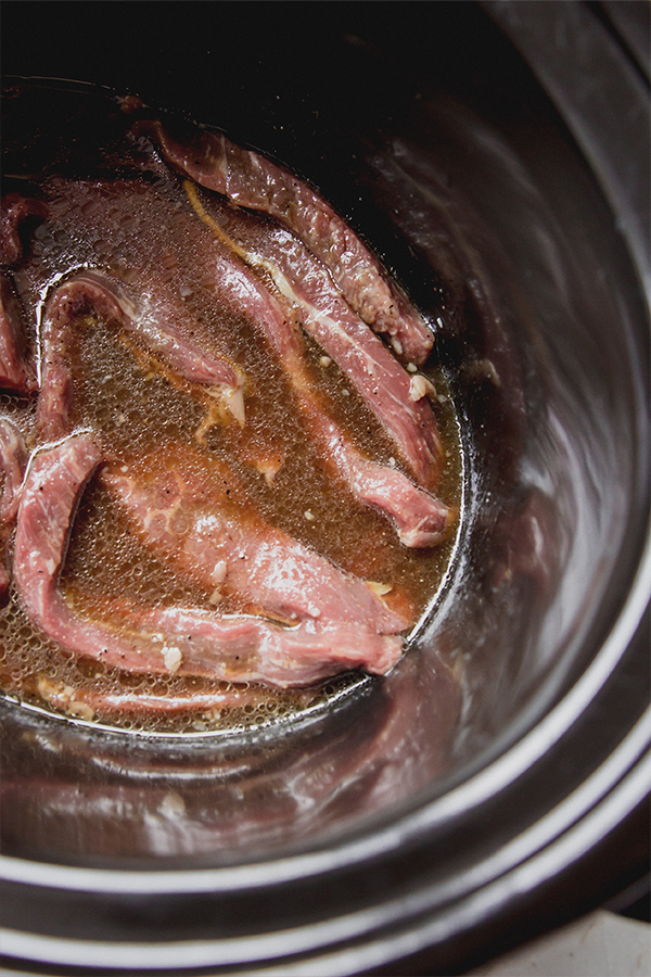 Strips of beef in a slow cooker.