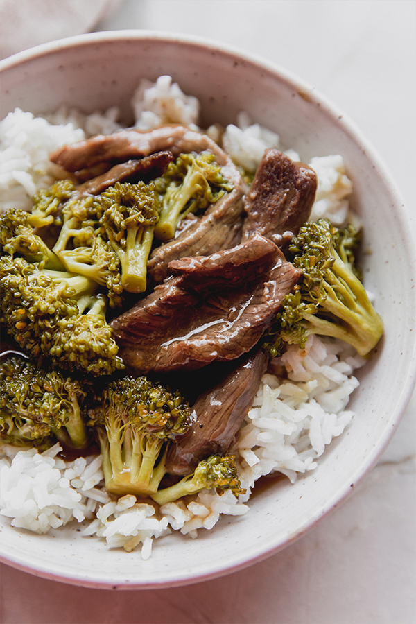 Bowl of rice topped with orange beef and broccoli.