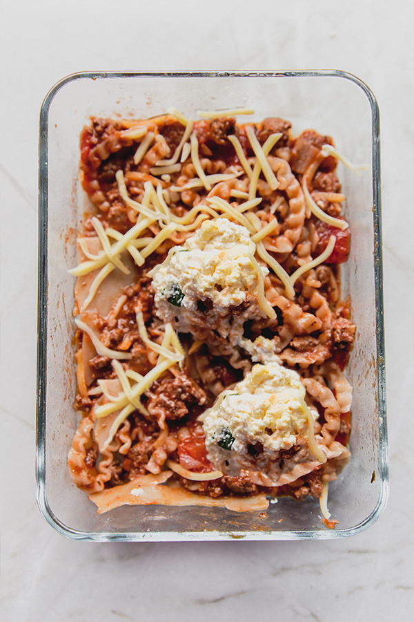 Uncooked lasagna in a glass container.