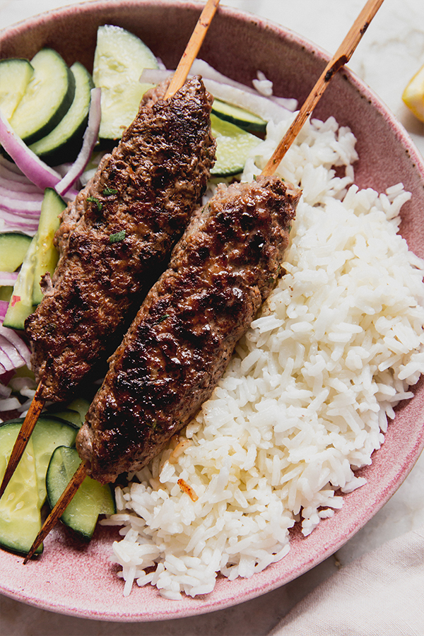 Two beef kofta over rice and vegetables.