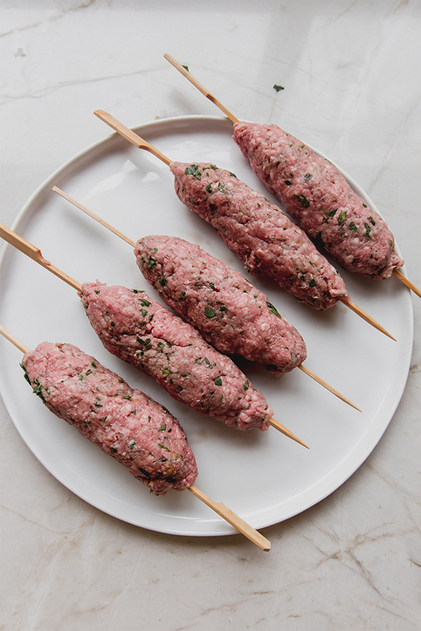 Several skewers with a raw beef mixture.