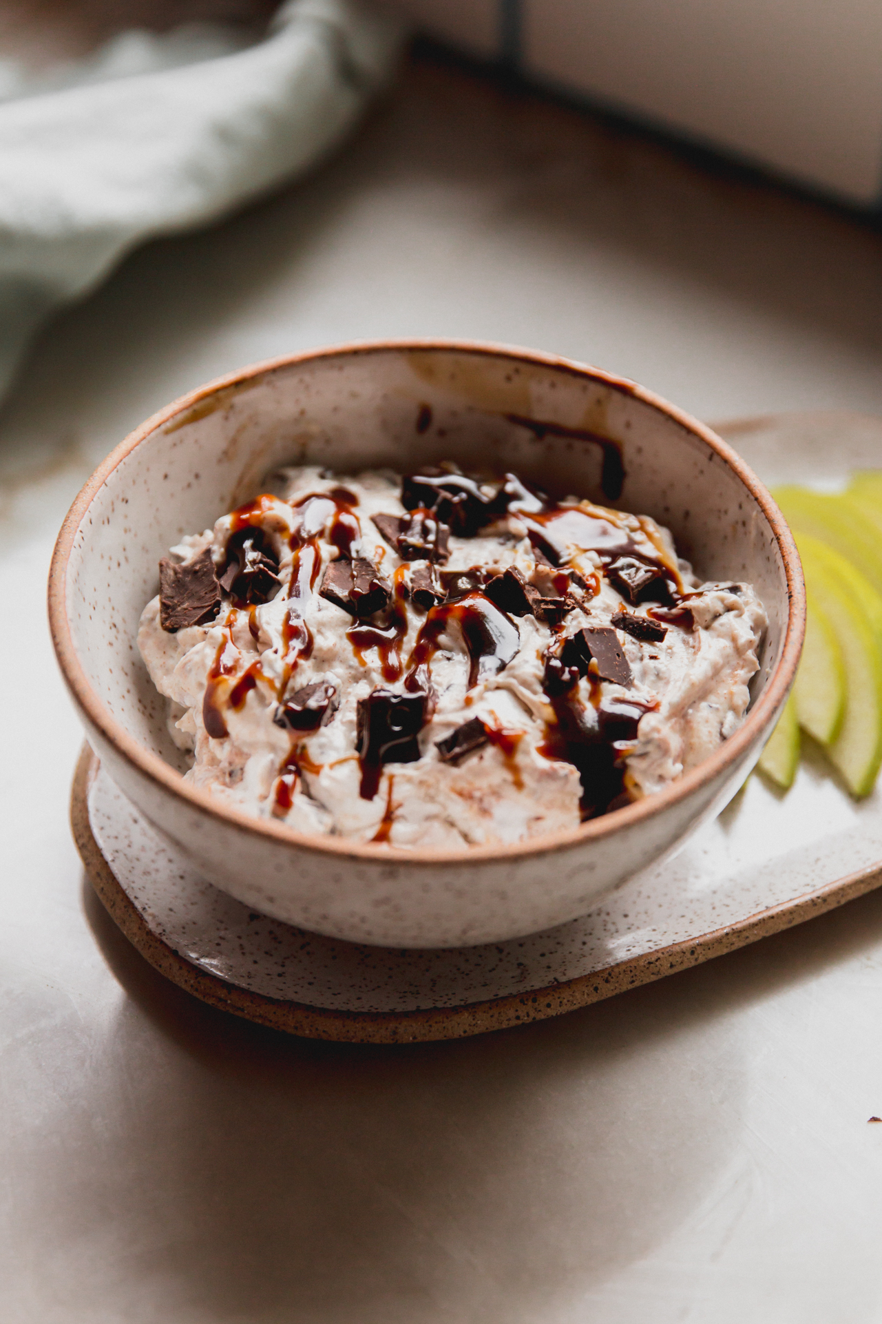 Snickers salad dip in a bowl topped with drizzled caramel and chopped chocolate.