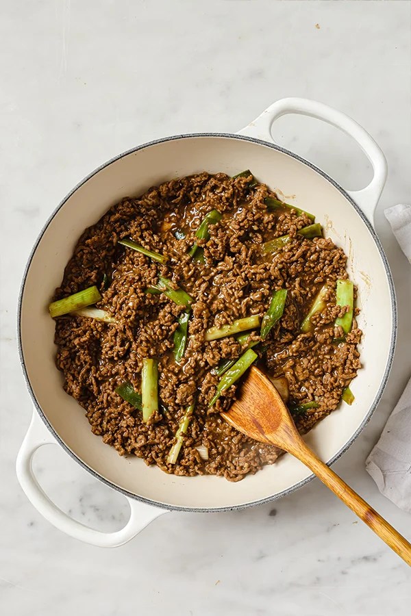 Wooden spoon stirring Mongolian ground beef.