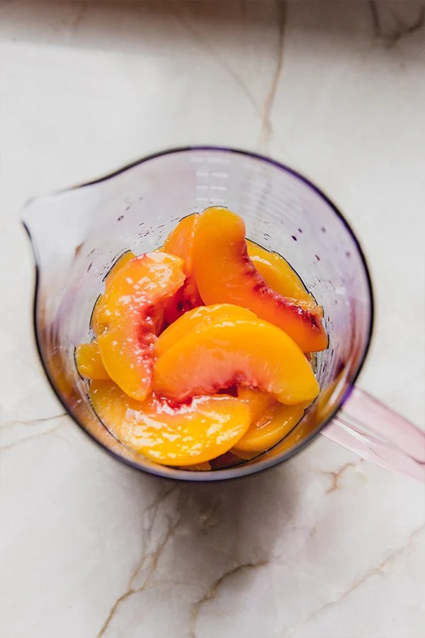 Peaches in a measuring cup in the process of making peach ring gummies.