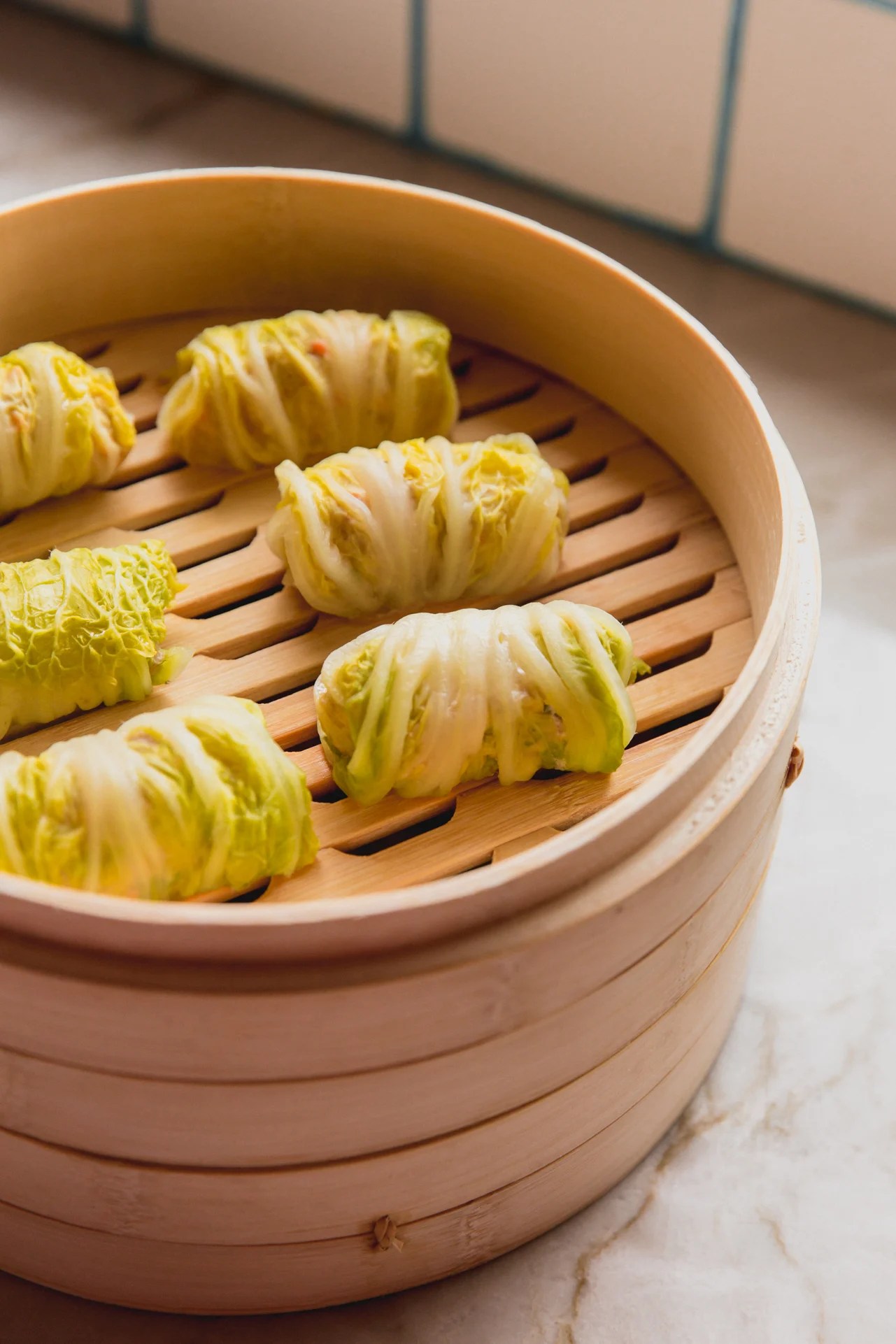 Several cabbage roll dumplings in a steamer.